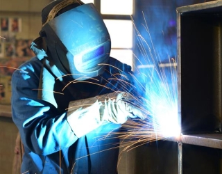 1547970-جوشکار-با-لباس-کار-در-حال-کار-بر-روی-قطعه-کار-در-یک-شرکت-صنعتی